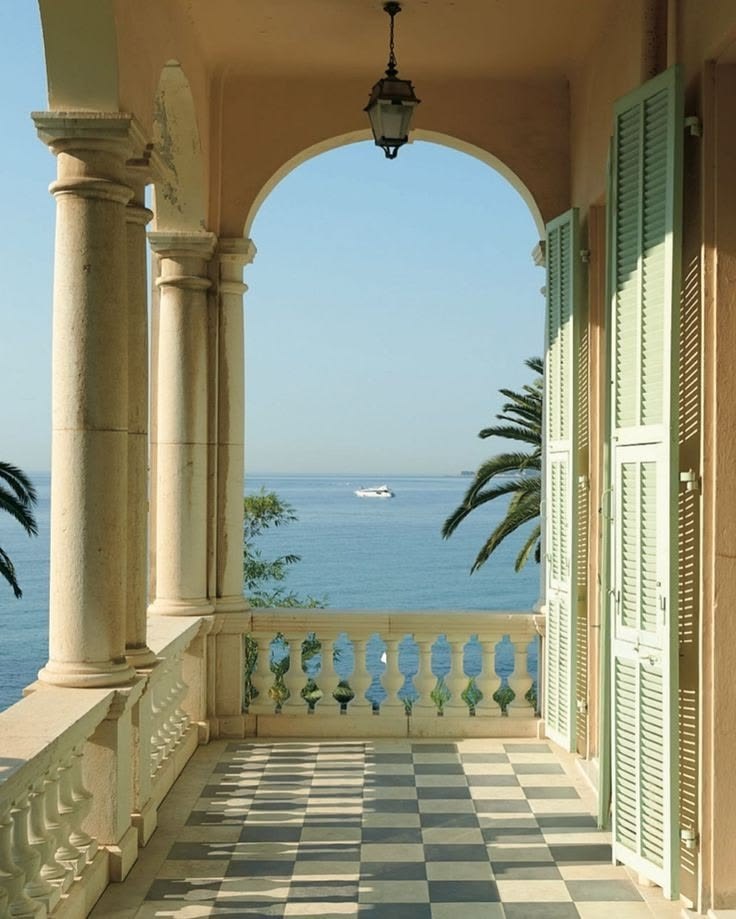 A stone loggia opening onto the sea, green shutters and a chequered floor.