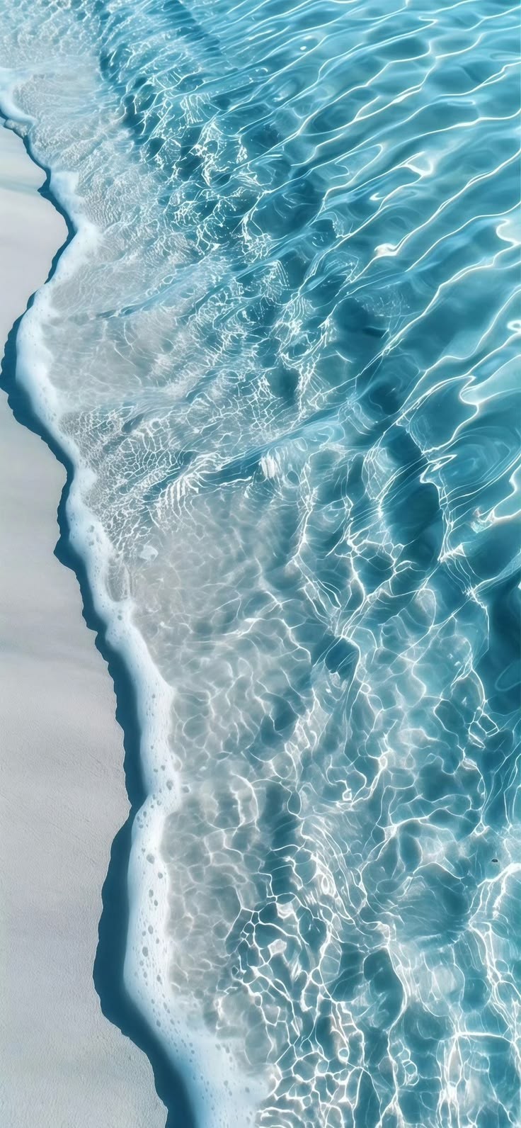 The sea from above, the surf breaking in pale bands.