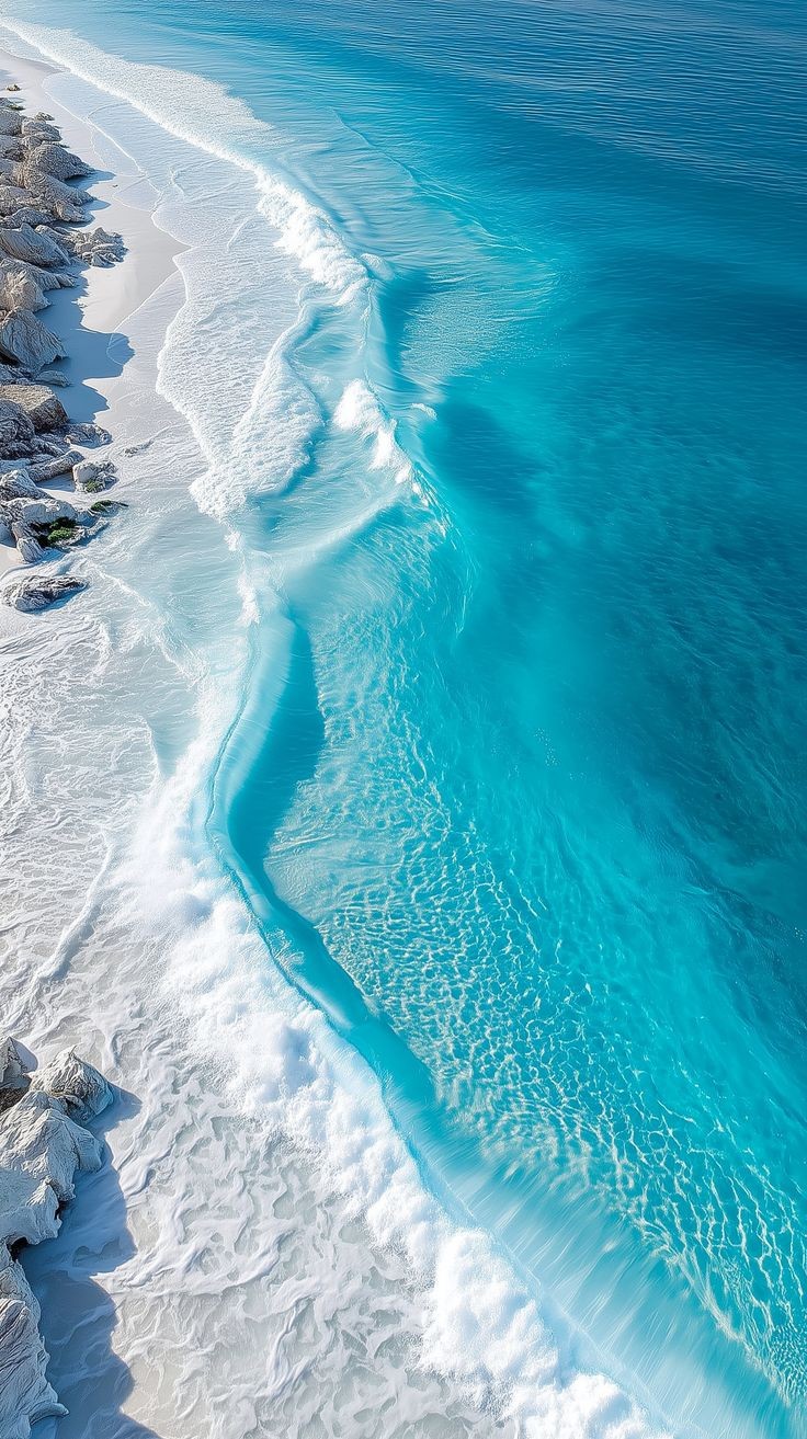 The shoreline from the air, white foam against deep blue.