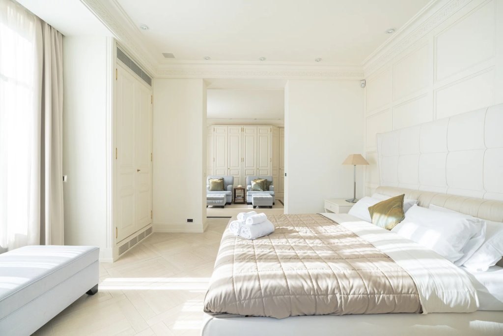 A bedroom in cream and white, the morning light across the floor.