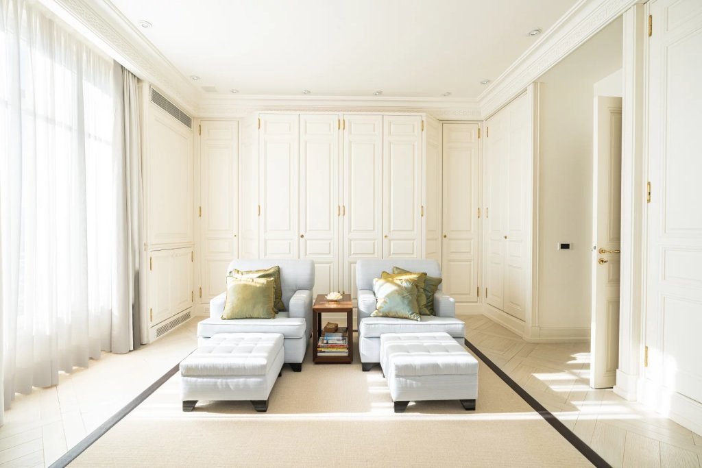 A quiet sitting room in cream, two armchairs facing the light.