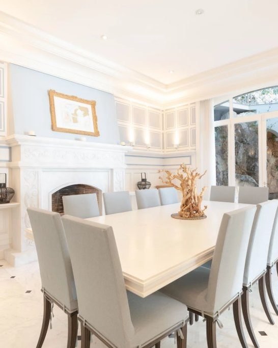 The dining room, the long white table set for ten.