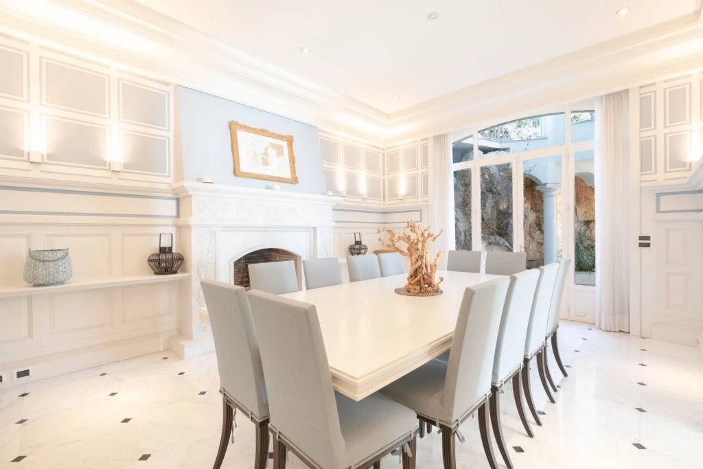 The dining room, the long white table set for ten beneath the moulded ceiling.