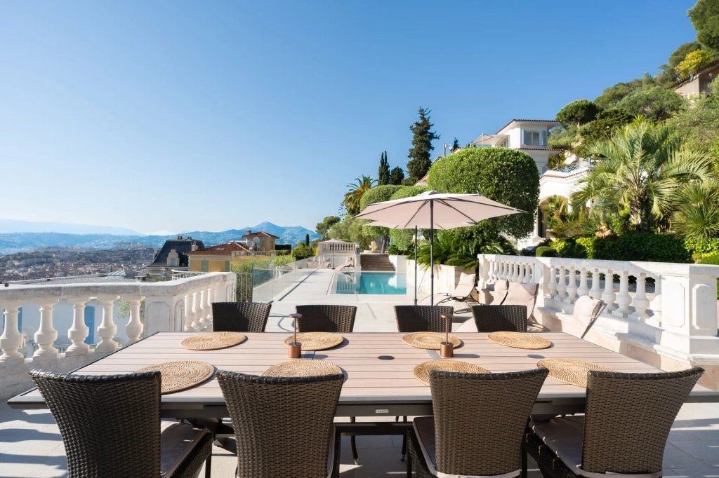 The long outdoor table set along the balustrade, the bay of Nice below.