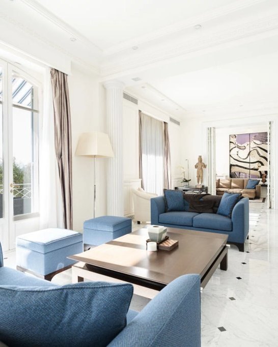 The salon of the villa, its blue sofas and the light from the terrace doors.